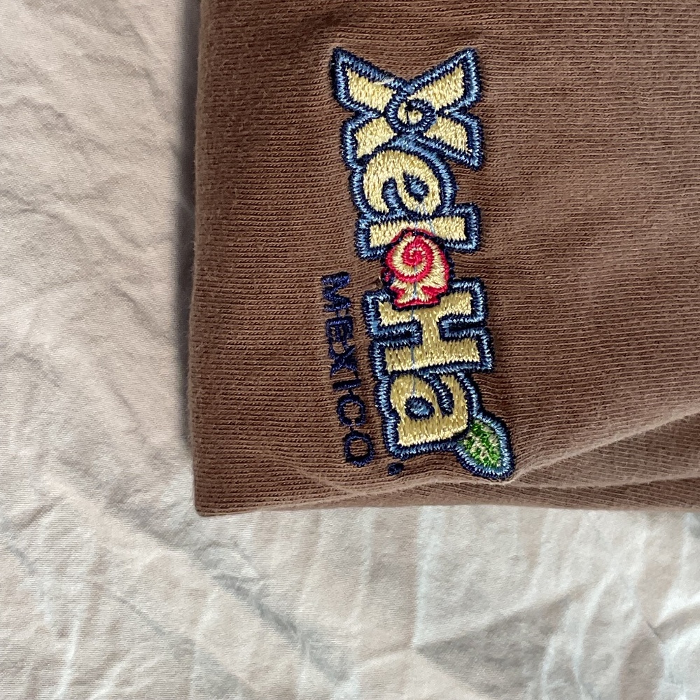 Chocolate brown XelHa polo shirt with tan collar.